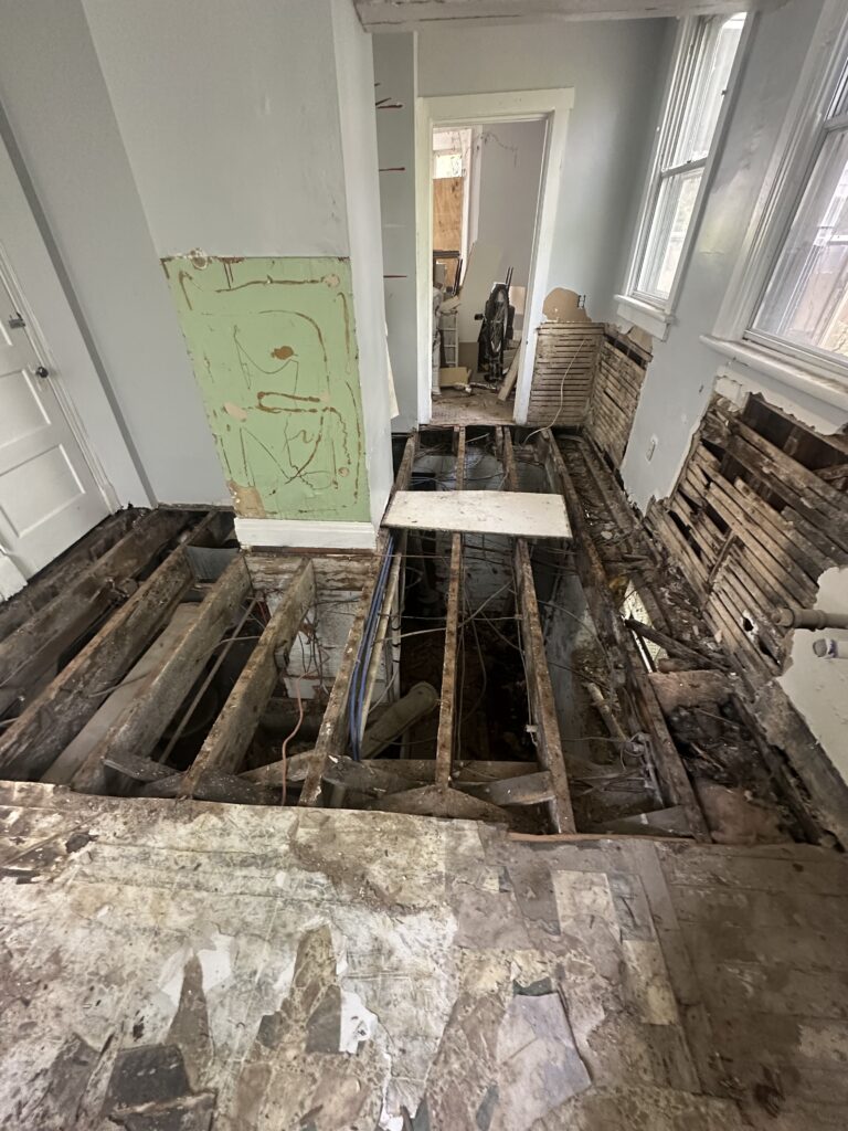 Damaged subfloor removed, exposing the floor joists